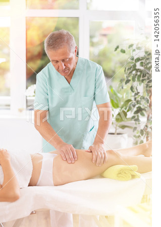 Skilled old masseur conducting hip massage for woman client 142056355