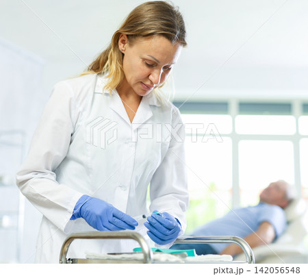 Concentrated woman doctor checking instruments for medical procedures Concentrated woman doctor checking instruments for medical procedures 142056548