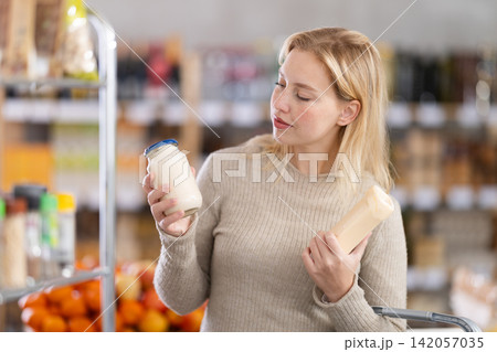 Young woman choosing mayonnaise in grocery store Young woman choosing mayonnaise in grocery store 142057035