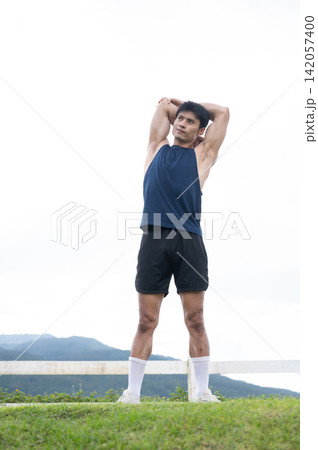 Athletic Asian Man Performing Triceps Stretch Outdoors 142057400