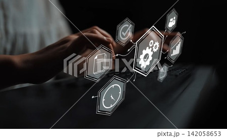 Business professional working on a laptop with digital icons representing technology, analytics, and gears floating above in a dark environment for innovation themes. Gluon Business professional working on a laptop with digital icons representing technology, analytics, and gears floating above in a dark environment for innovation themes. Gluon 142058653