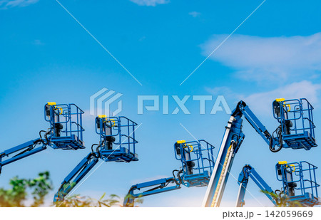 Articulated boom lift fleet with telescopic aerial work platforms against sky. Construction equipment rental, industrial maintenance, hydraulic access systems, engineering services and elevated work. Articulated boom lift fleet with telescopic aerial work platforms against sky. Construction equipment rental, industrial maintenance, hydraulic access systems, engineering services and elevated work. 142059669