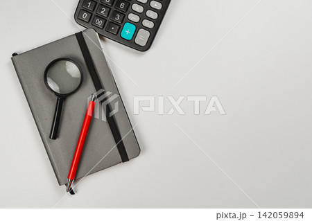 Calculating finances with tools on a table in a workspace Calculating finances with tools on a table in a workspace 142059894