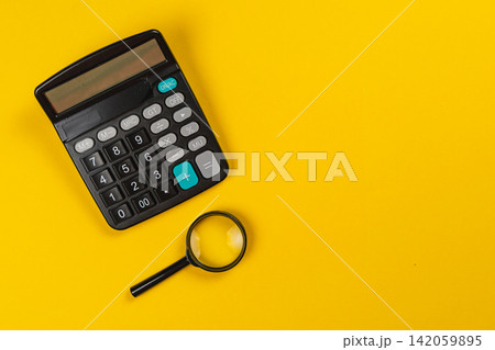 Calculator and magnifying glass on yellow background for finance tasks Calculator and magnifying glass on yellow background for finance tasks 142059895