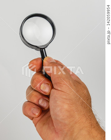 Holding a magnifying glass for investigation and detailed examination Holding a magnifying glass for investigation and detailed examination 142059954