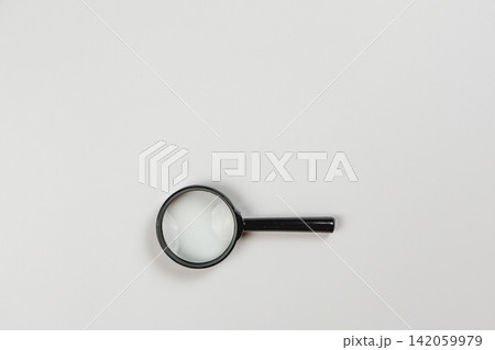 Magnifying glass on a plain surface waiting for close inspection and analysis 142059979