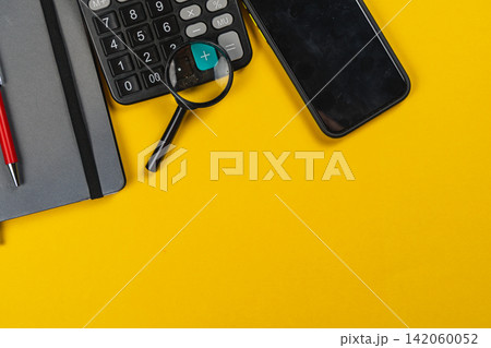 Tools for finance planning on a yellow surface with calculator and smartphone Tools for finance planning on a yellow surface with calculator and smartphone 142060052