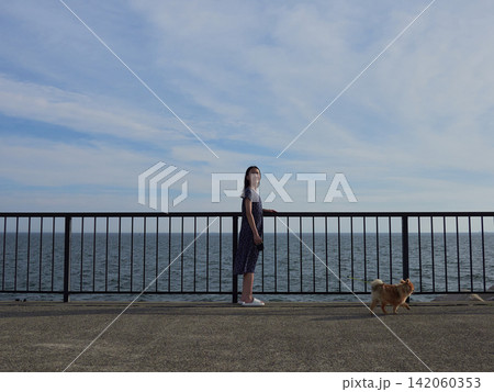 夏の海の海岸で可愛いポメラニアンの子犬を連れて散歩する十代の女の子の子供の姿 夏の海の海岸で可愛いポメラニアンの子犬を連れて散歩する十代の女の子の子供の姿 142060353