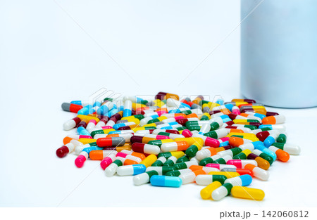 Colorful capsule pills near plastic drug bottle. Multi-colored capsule pills on white table. Pharmacy drugstore products. Pharmaceutical industry. Health budget and policy. Bright colors capsule pills Colorful capsule pills near plastic drug bottle. Multi-colored capsule pills on white table. Pharmacy drugstore products. Pharmaceutical industry. Health budget and policy. Bright colors capsule pills 142060812