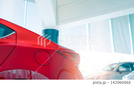 Closeup fuel tank door of red car. New and shiny luxury car parked in modern showroom for sale. Car dealership office. Electric car business concept. Automobile leasing. Automotive industry. Closeup fuel tank door of red car. New and shiny luxury car parked in modern showroom for sale. Car dealership office. Electric car business concept. Automobile leasing. Automotive industry. 142060868