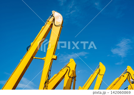 Yellow backhoe with hydraulic piston arm against clear blue sky. Heavy machine for excavation in construction site. Hydraulic machinery. Huge bulldozer. Heavy industry 142060869