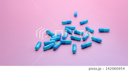 Blue antibiotic capsule pills spread on pink background. Antibiotic drug resistance. Pharmaceutical industry. Healthcare and medicine concept. Health budget concept. Capsule manufacturing industry. Blue antibiotic capsule pills spread on pink background. Antibiotic drug resistance. Pharmaceutical industry. Healthcare and medicine concept. Health budget concept. Capsule manufacturing industry. 142060954