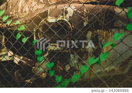 Abandoned rusty truck behind wire fence in industrial scrapyard. Vehicle decay, weathered metal, economic recession, financial loss, urban abandonment and transportation failure. financial recession. 142060988