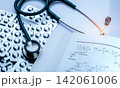 Stethoscope with pharmaceutical blister packs and medical research document on desk. Healthcare diagnostics, hospital medicine, clinical pharmacy, drug development and medical science concepts. 142061006