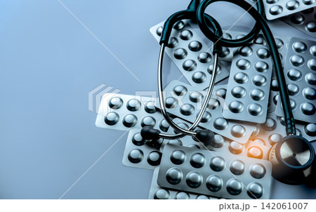 Medical stethoscope with pharmaceutical blister packs on blue background. Hospital healthcare, clinical diagnosis, pharmacy products, prescription medicine and medical service. Pharmaceutical industry 142061007