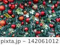 Close up of richly decorated Christmas tree with red baubles, glitter ornaments, evergreen branches and festive decorations creating vibrant holiday background for Christmas and New Year celebrations. 142061012