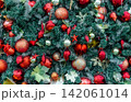 Close up of richly decorated Christmas tree with red baubles, glitter ornaments, evergreen branches and festive decorations creating vibrant holiday background for Christmas and New Year celebrations. 142061014