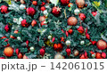 Close up of richly decorated Christmas tree with red baubles, glitter ornaments, evergreen branches and festive decorations creating vibrant holiday background for Christmas and New Year celebrations. 142061015