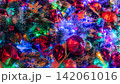 Close up of colorful Christmas tree illuminated with glowing LED lights, red baubles, glitter ornaments and evergreen branches creating festive background for holiday and New Year celebrations. 142061016