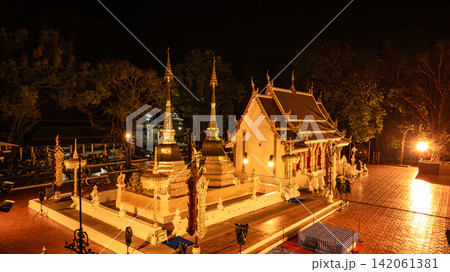 Doi Tung summit reveals a sacred golden Thai temple illuminated at night, traditional Buddhist architecture, cultural heritage, and radiant golden light in a 2023 aerial view. 142061381