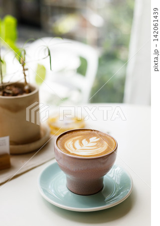 Cup of hot latte coffee on table by the window. Cup of hot latte coffee on table by the window. 142061439
