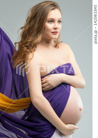Pregnant woman posing in purple and yellow fabric Pregnant woman posing in purple and yellow fabric 142061845