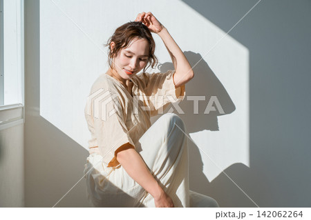 西陽の当たる窓辺にいる女性（モデル,ファッション,光,影） 142062264