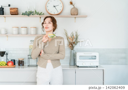キッチンカウンターでデトックスウォーターを飲む女性 キッチンカウンターでデトックスウォーターを飲む女性 142062409