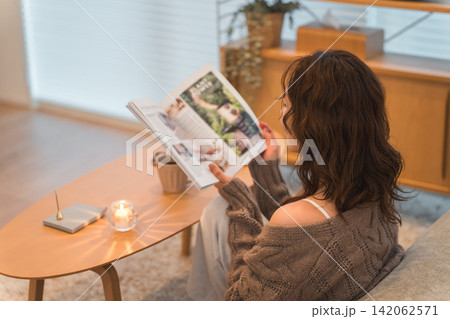 夜のリビングに座り雑誌を読むオシャレなアジア人女性 142062571