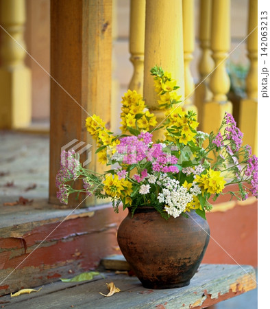 Flowers of loosestrife and yarrow on an old wooden veranda of a country house. Flowers of loosestrife and yarrow on an old wooden veranda of a country house. 142063213