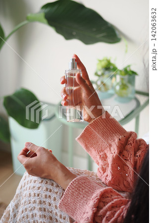 Spraying fragrance in a cozy indoor setting Spraying fragrance in a cozy indoor setting 142063632