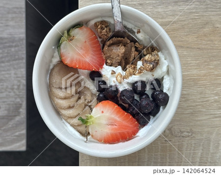 Creamy yogurt bowl topped with fresh fruits and crunchy toppings, offering a smooth texture and refreshing taste. Light, wholesome, and visually appealing, perfect for breakfast or healthy snack. 142064524