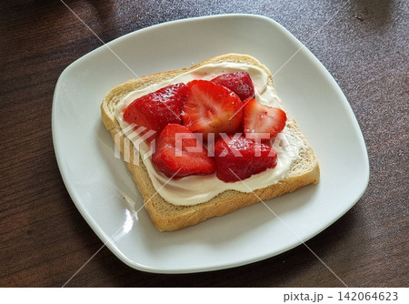 Japanese fruit sando with fluffy white bread, fresh cream, and vibrant slices of seasonal fruits like strawberries, kiwis, and mangoes. A refreshing, colorful treat perfect for any occasion. 142064623