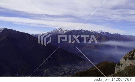 Snowy alpine peaks above a misty mountain valley 142064767