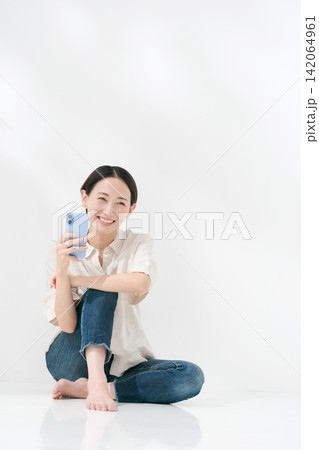 スマホを見る女性の全身ポートレート スマホを見る女性の全身ポートレート 142064961