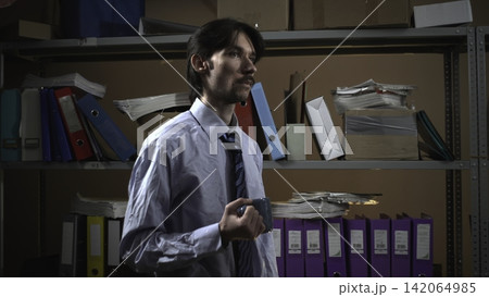 Businessman holding a marker in a dim archive room Businessman holding a marker in a dim archive room 142064985