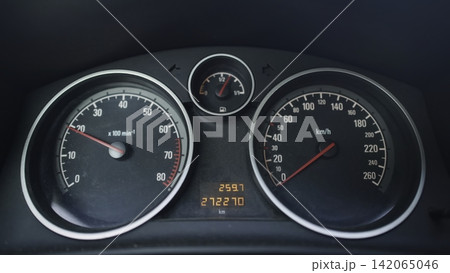 Car instrument cluster with circular speedometer, tachometer, fuel gauge, and digital odometer, illuminated inside dark vehicle interior with clean markings, metallic trim, and subtle needle movement Car instrument cluster with circular speedometer, tachometer, fuel gauge, and digital odometer, illuminated inside dark vehicle interior with clean markings, metallic trim, and subtle needle movement 142065046