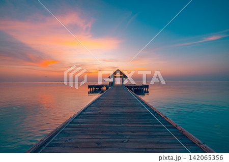 Breathtaking wooden jetty stretching over calm azure lagoon glowing pastel dusk Maldives resort. Luxury travel honeymoon paradise scenic. Exotic getaway wallpaper decor Breathtaking wooden jetty stretching over calm azure lagoon glowing pastel dusk Maldives resort. Luxury travel honeymoon paradise scenic. Exotic getaway wallpaper decor 142065356