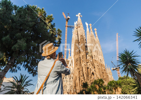 Woman traveler taking photo of Sagrada Familia cathedral in Barcelona with smartphone on sunny day Woman traveler taking photo of Sagrada Familia cathedral in Barcelona with smartphone on sunny day 142066341