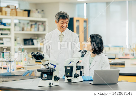 実験室で研究を行う白衣姿の男女研究者 実験室で研究を行う白衣姿の男女研究者 142067145