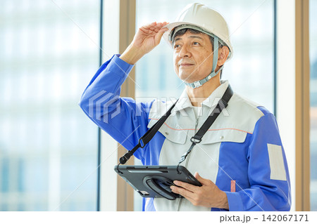 ヘルメット姿でタブレットを持つシニア男性技術者 ヘルメット姿でタブレットを持つシニア男性技術者 142067171