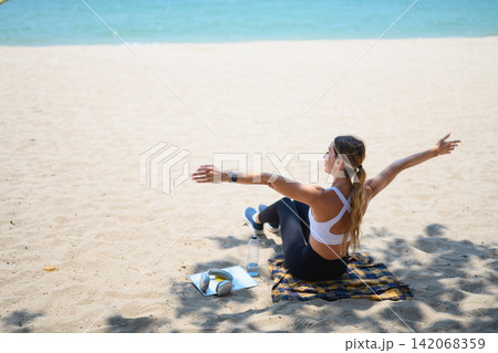 Young woman sitting on the sand with open arms enjoying summer vacation and freedom Young woman sitting on the sand with open arms enjoying summer vacation and freedom 142068359
