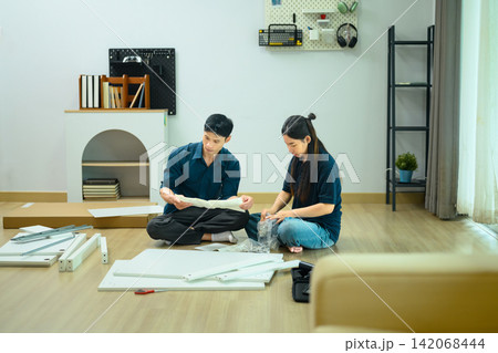 Asian Couple Assembling Flat Pack Furniture Together on Living Room Floor Asian Couple Assembling Flat Pack Furniture Together on Living Room Floor 142068444