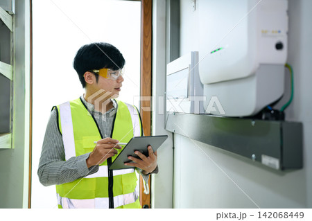 Asian Engineer Inspecting Solar Inverter System with Tablet Indoor Installation Check Asian Engineer Inspecting Solar Inverter System with Tablet Indoor Installation Check 142068449