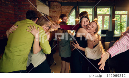 Office colleagues hugging and celebrating together after joyful company event Office colleagues hugging and celebrating together after joyful company event 142069212