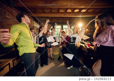 Coworkers dancing between desks during vibrant office celebration 142069213