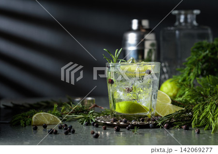 Cocktail Gin and tonic with ice, juniper berries, and a lime wedges. Cocktail Gin and tonic with ice, juniper berries, and a lime wedges. 142069277