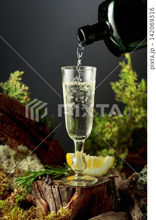 Vintage gin or herbal bitter poured from an antique bottle into a glass. Vintage gin or herbal bitter poured from an antique bottle into a glass. 142069316