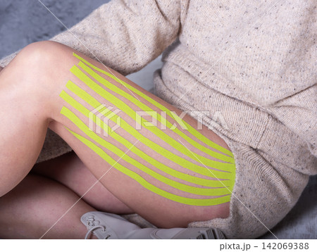 Lymphatic drainage kinesiology taping on female thigh, yellow green tape 142069388