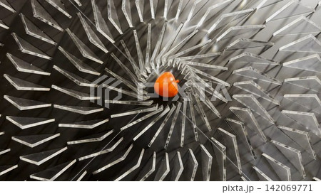 Top view on spiral geometric installation with metallic radial elements surrounding a red apple-shaped object in the center. Strong symmetry, depth and optical movement create a striking visual focus Top view on spiral geometric installation with metallic radial elements surrounding a red apple-shaped object in the center. Strong symmetry, depth and optical movement create a striking visual focus 142069771
